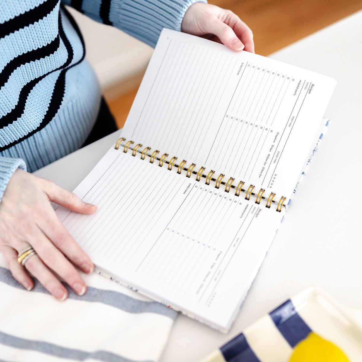 Angled view of a personalized recipe binder with blue and white gingham cover and gold spiral binding