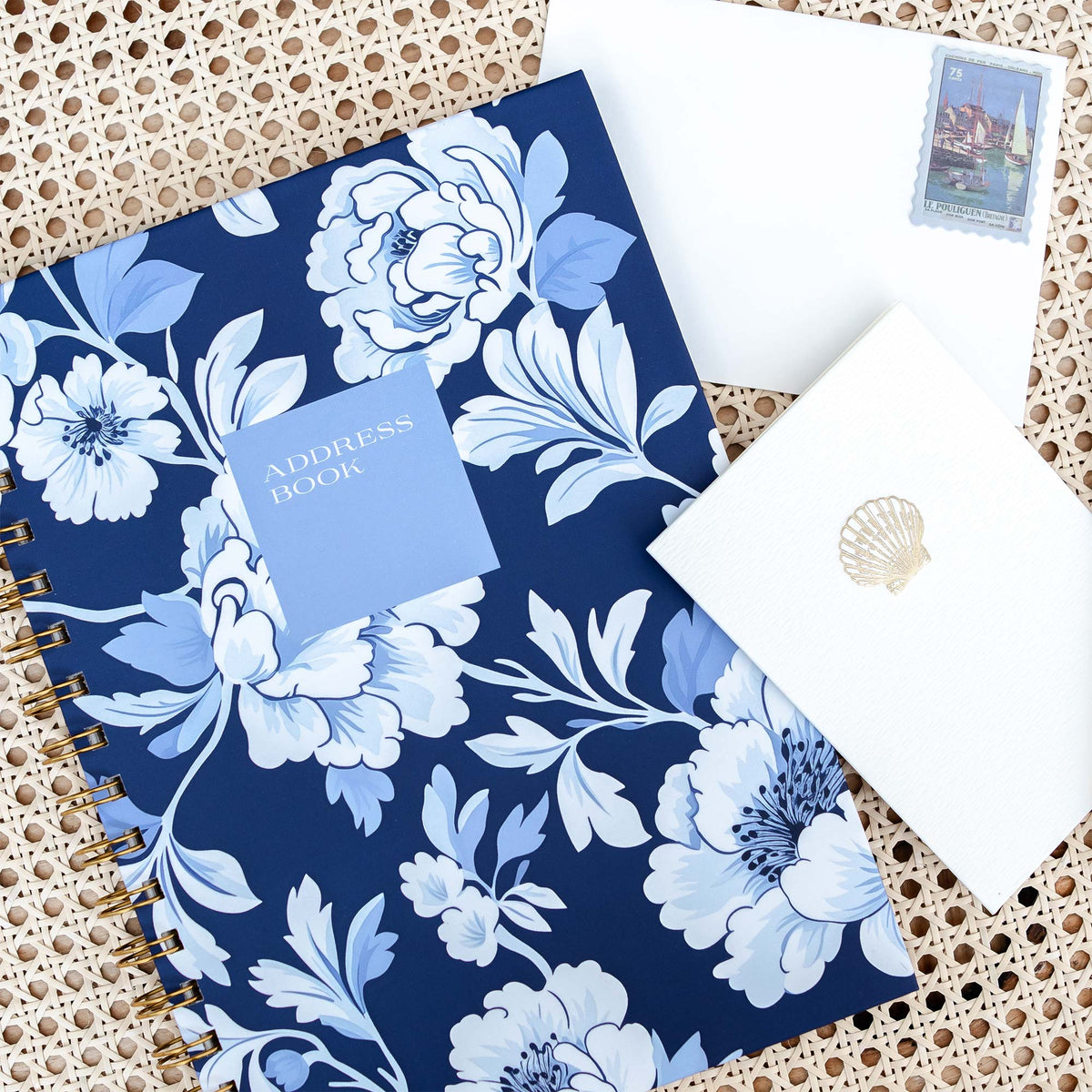 Angled view of a personalized address book with blue and white peony floral cover and gold spiral binding