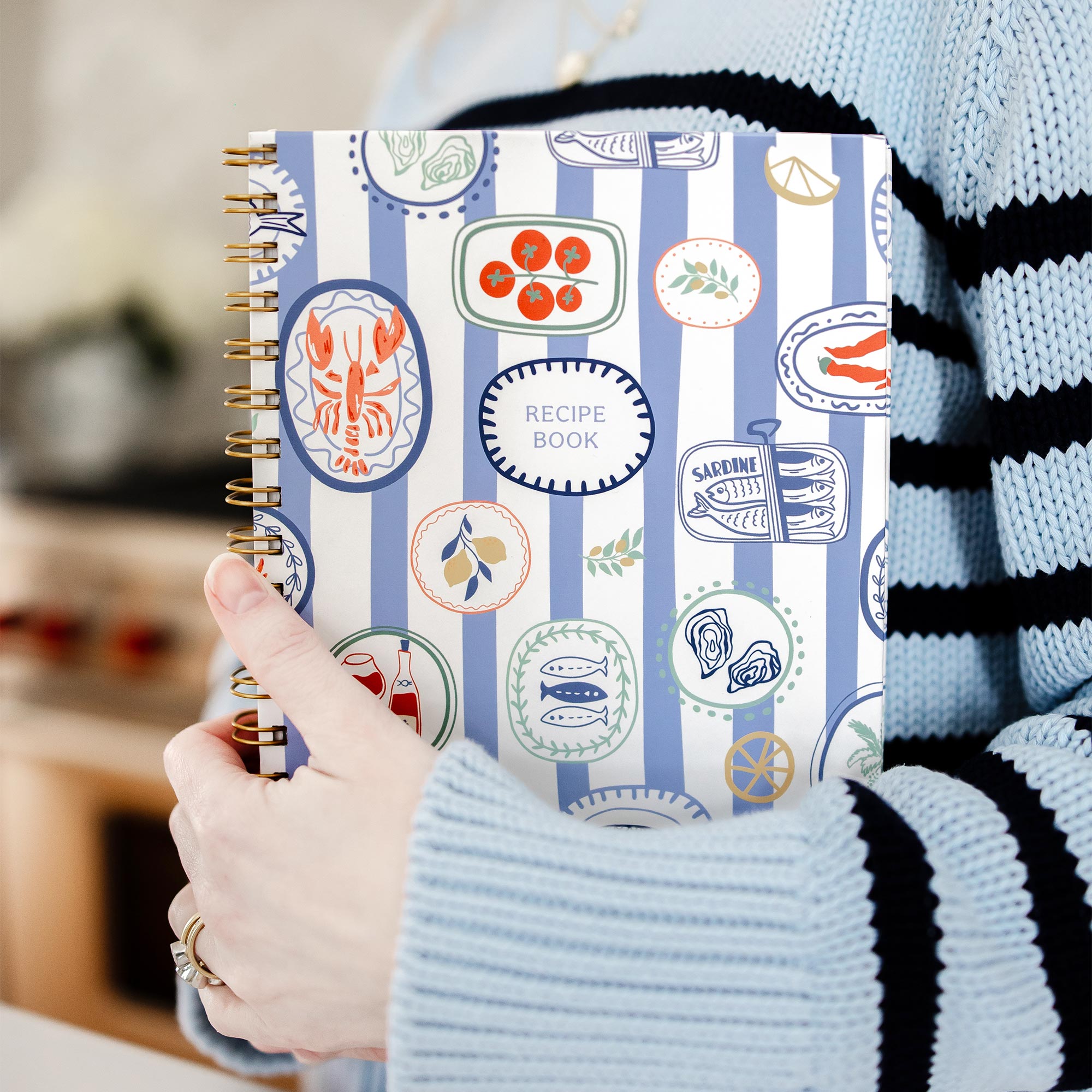 Styled image featuring a Keepsake Paper Co. recipe journal with an Italian summer vibes pattern held by a woman in a kitchen