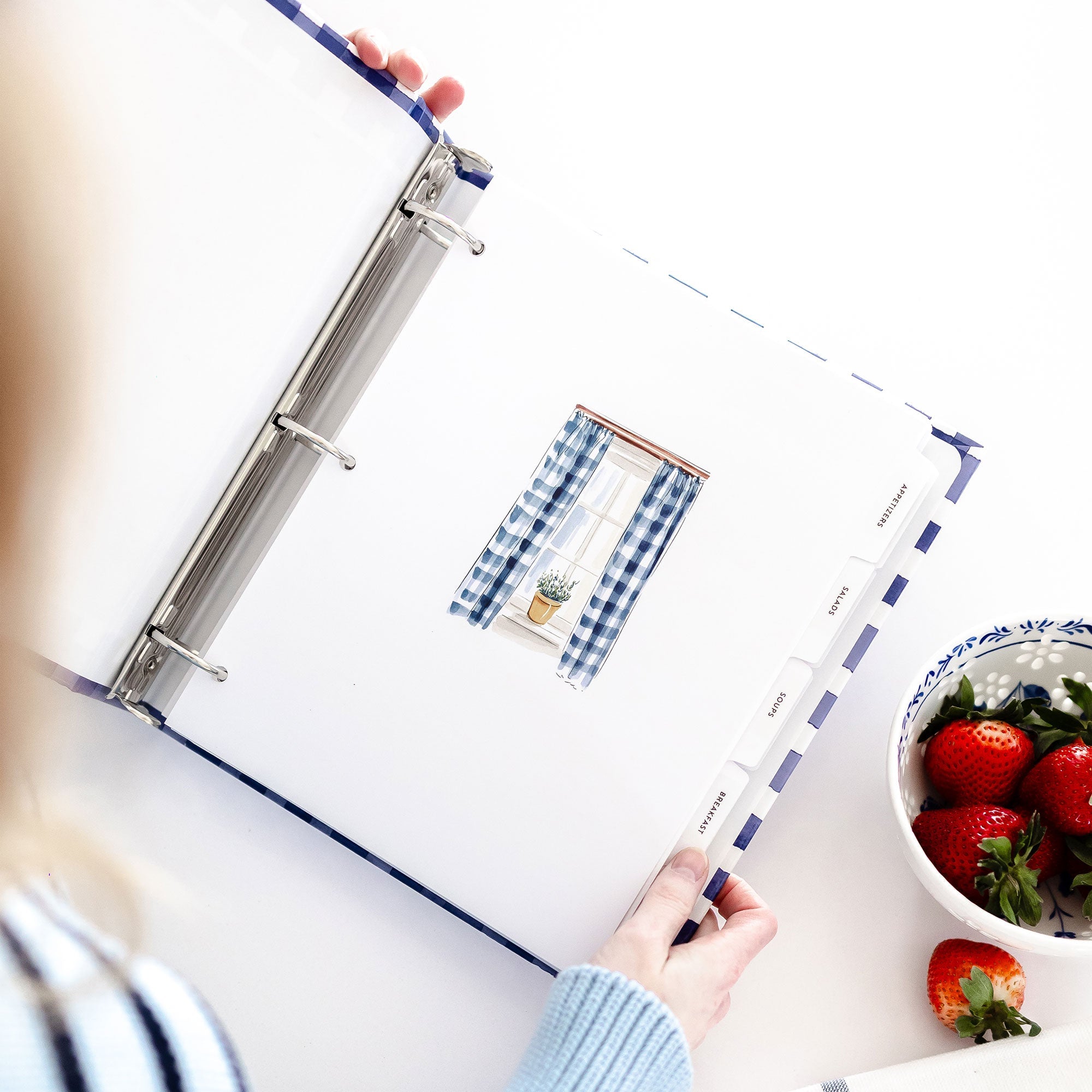 Angled view of Keepsake Paper Co. recipe divider tabs inside an open blue and white gingham binder
