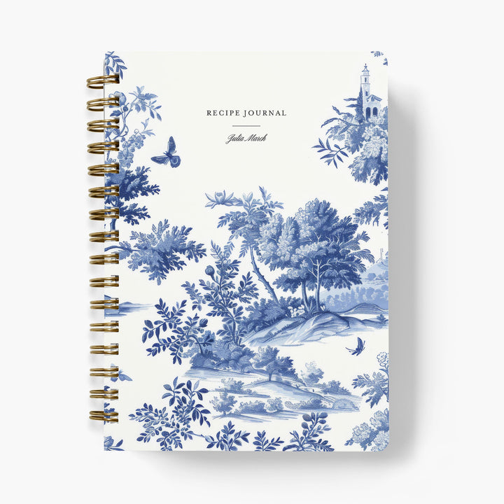 Custom recipe journal with blue and white toile pattern on a white background with gold wire binding