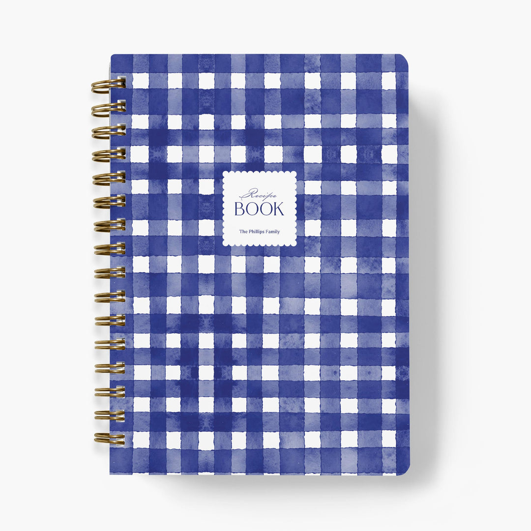 Custom recipe journal with blue and white gingham pattern with gold spiral binding on a white background