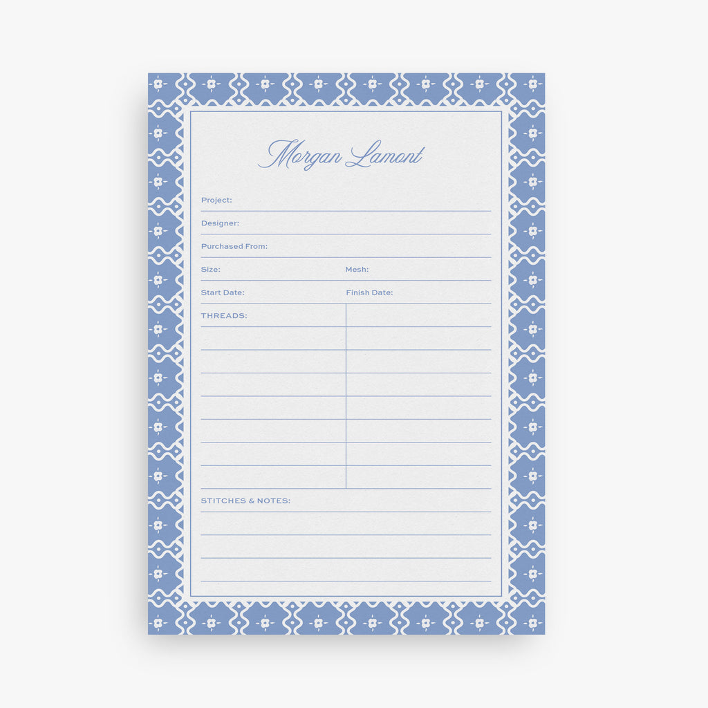 Custom needlepoint project notepad with blue decorative border and text on a white background