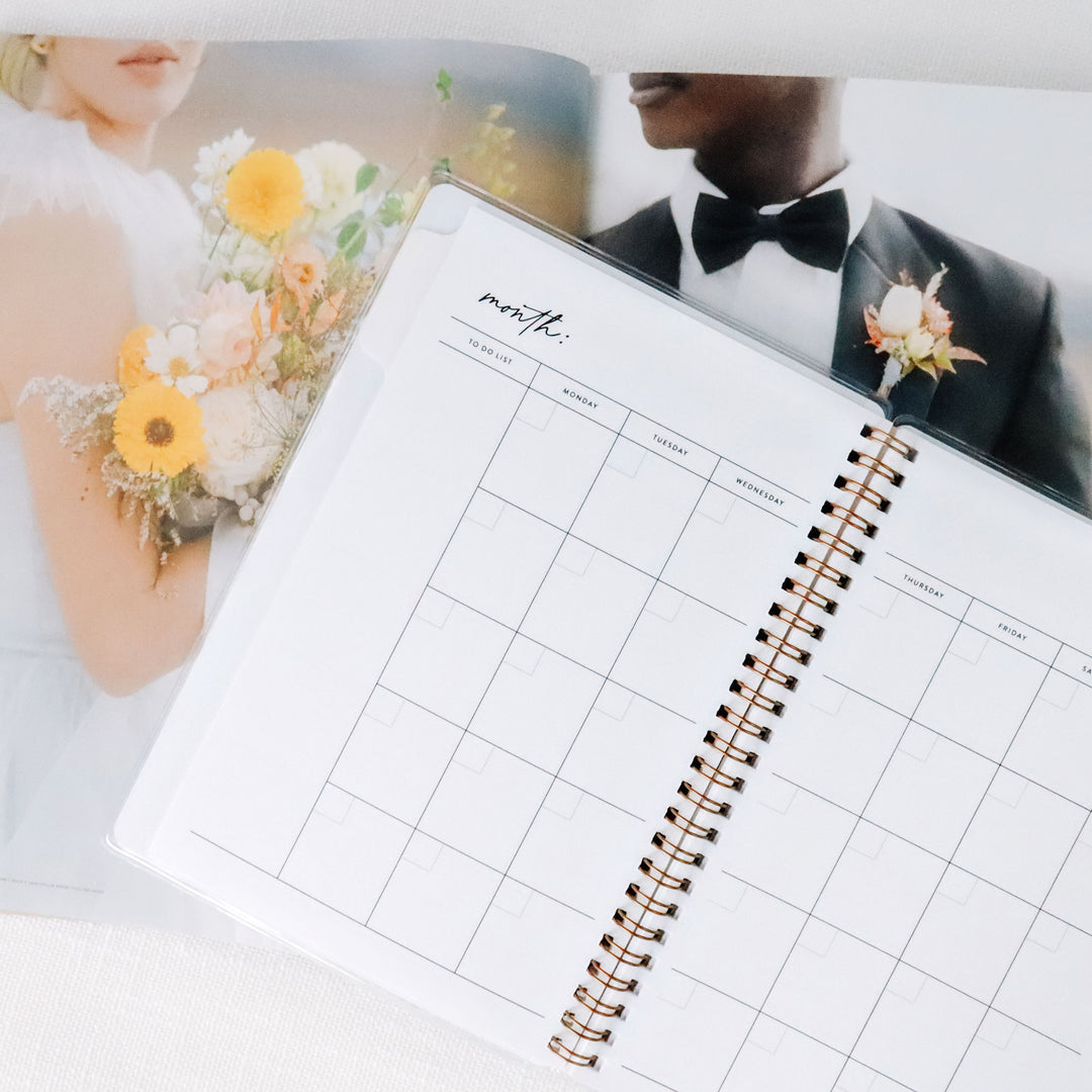 Open wedding planner showing blank undated monthly calendar in a 2-page spread, start planning your wedding at any month