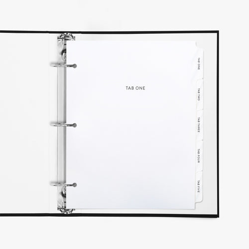 Custom white binder divider tabs with personalized section titles shown inside a standard 3-ring binder