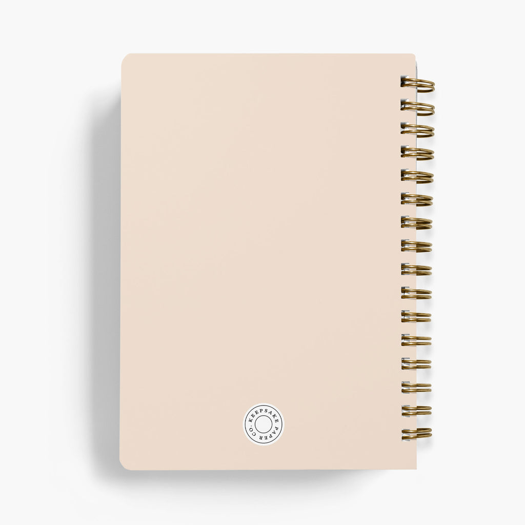 Back view of a wedding notebook with gold spiral binding on a white background