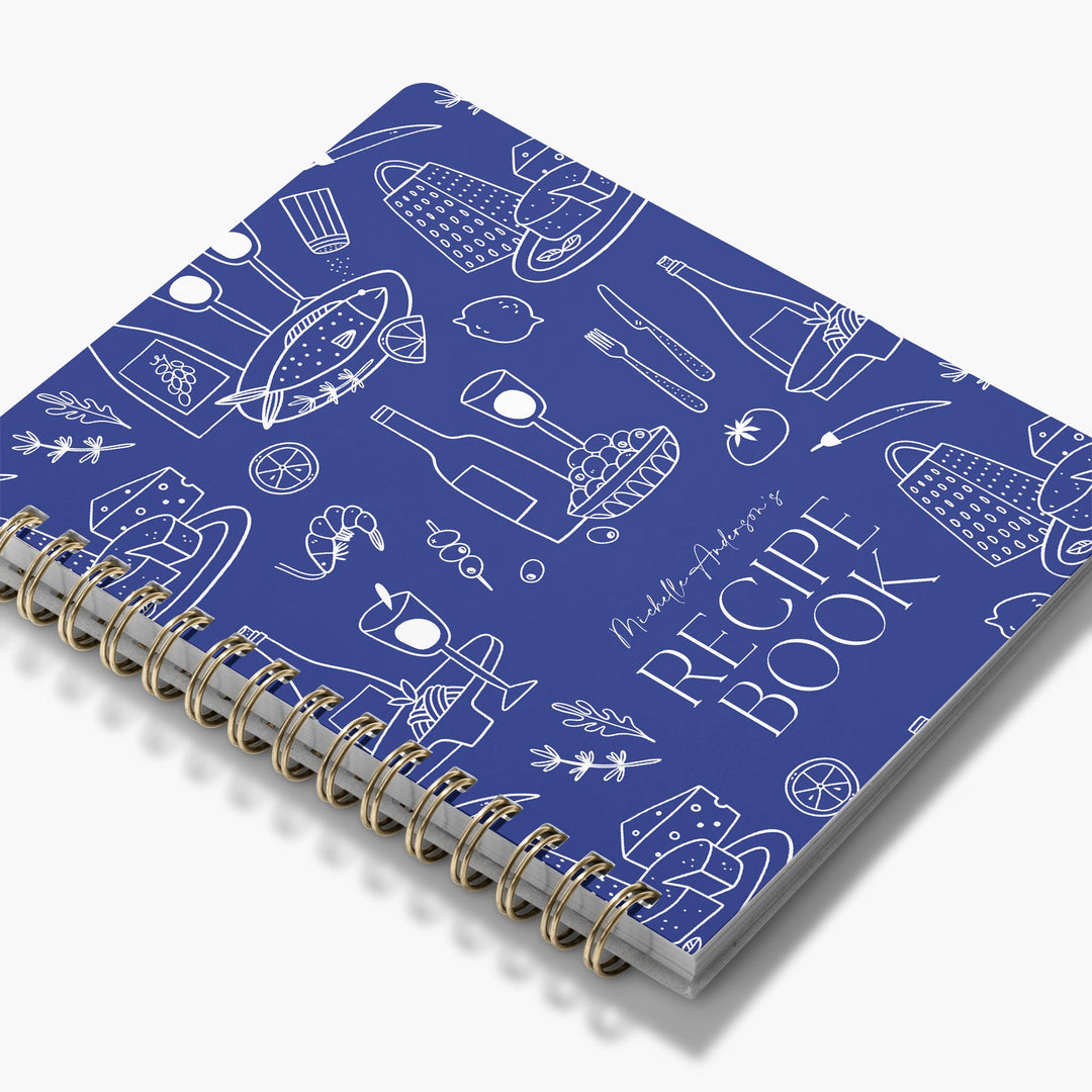 Custom recipe book with blue cover and white food illustrations on a white background