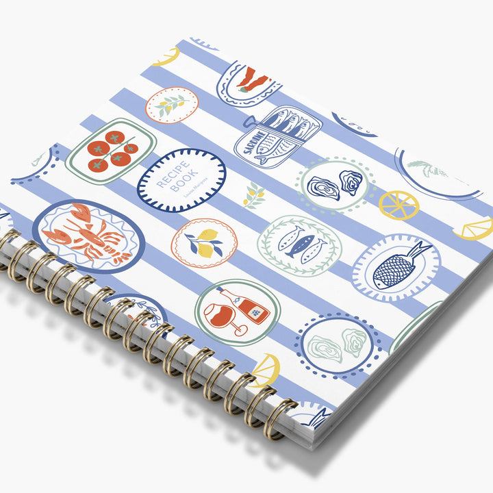 Custom cookbook with a colorful design on the cover featuring Mediterranean food items like lobster and lemons.