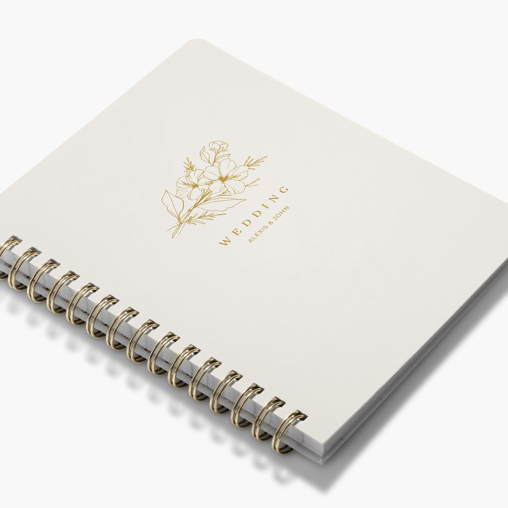 Angled view of a custom wedding book with gold floral design and text on a white background