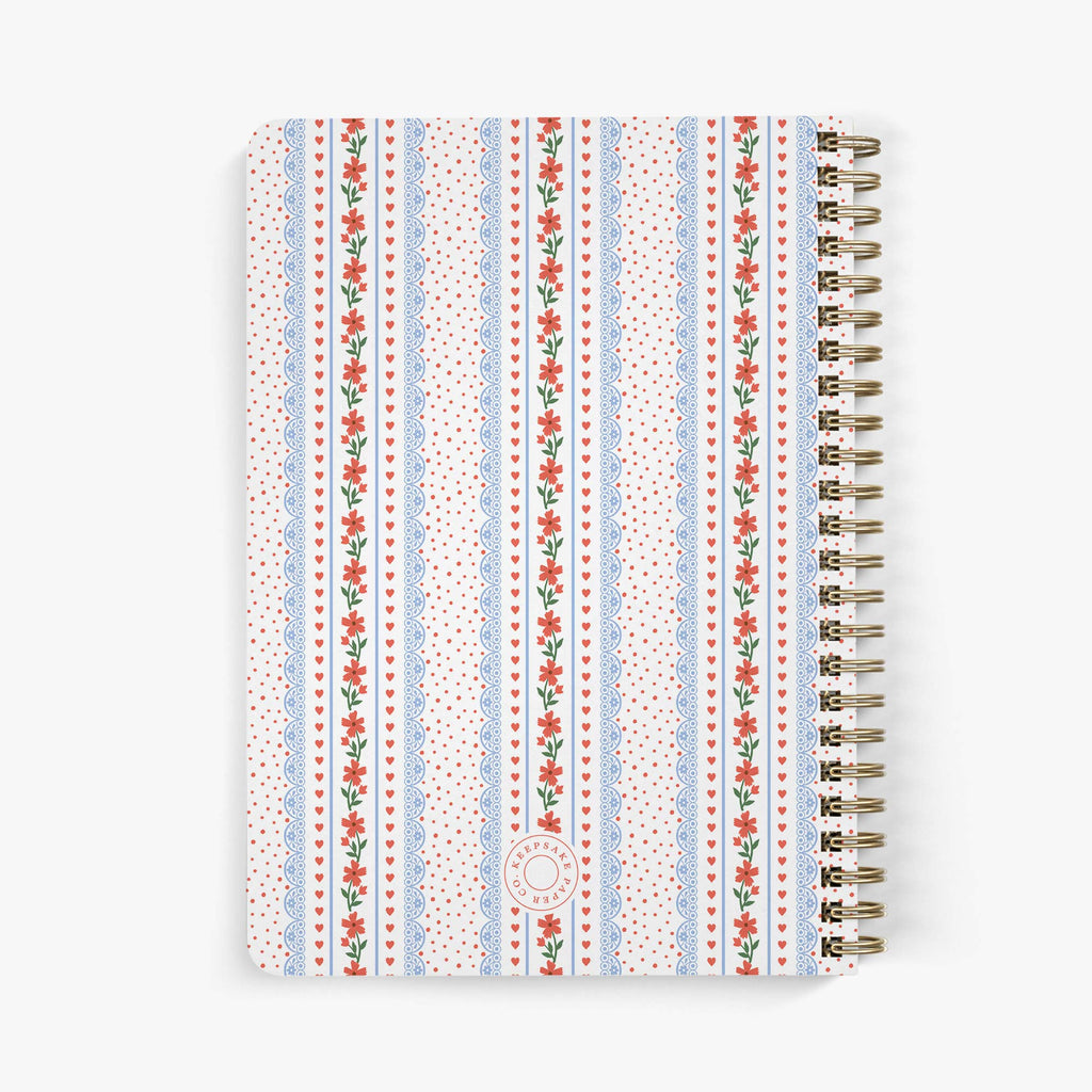 Back view of needlepoint journal with  hearts and floral patterned cover on a white background