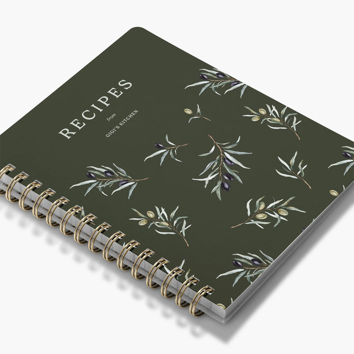Custom cookbook with bunches of olives and leaves with gold spiral binding on a white background