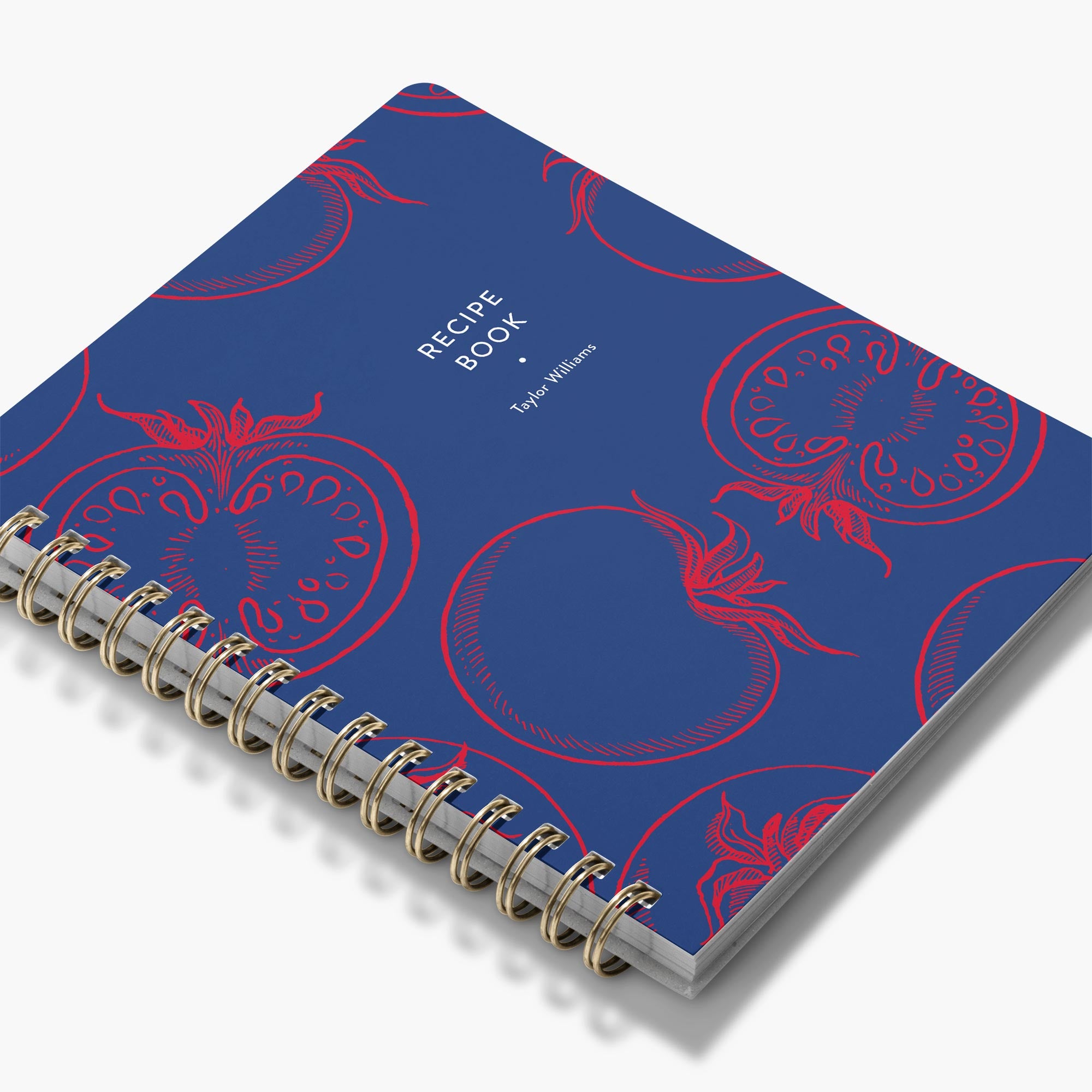 Custom cookbook with red tomato pattern on a navy background with gold spiral binding