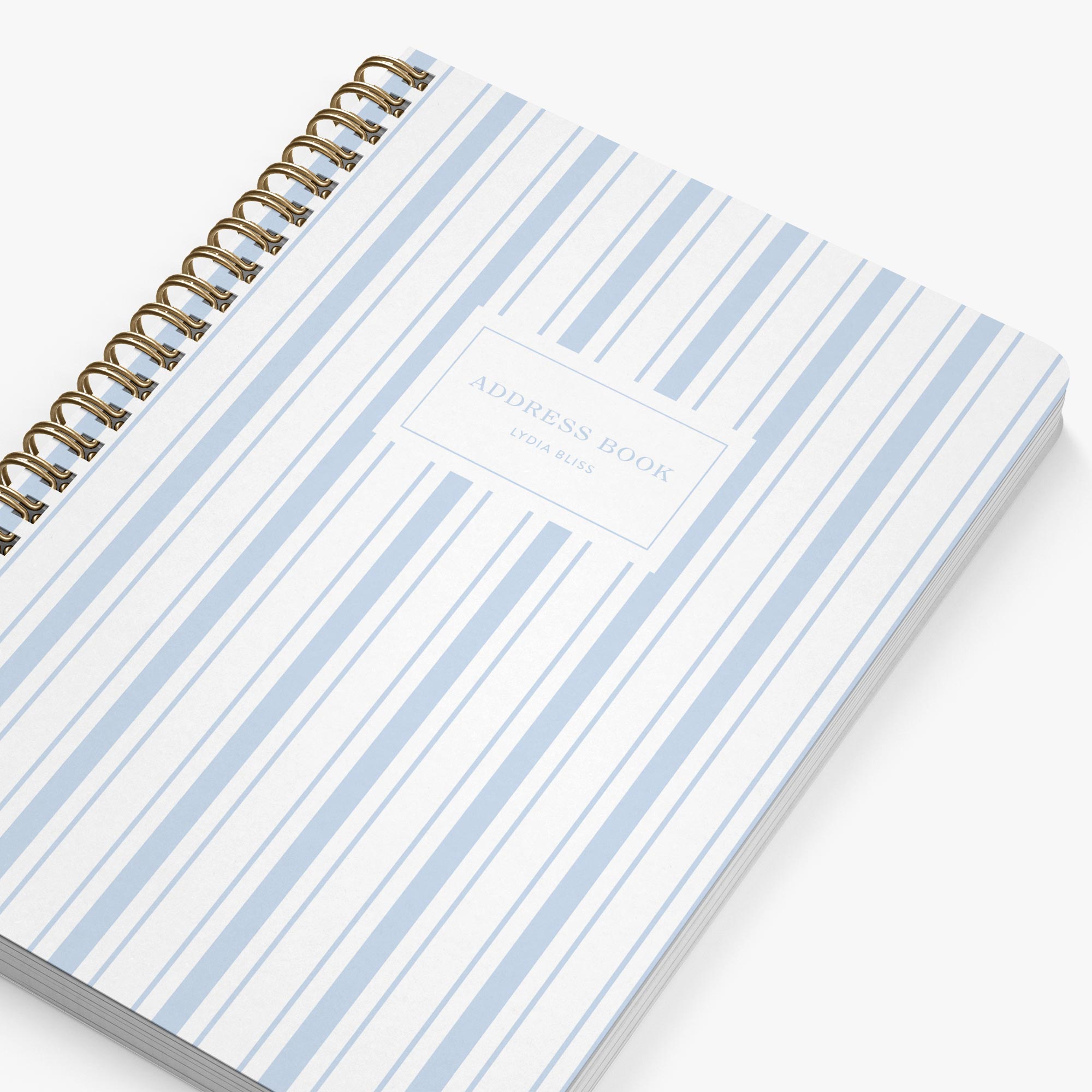 Notebook with blue and white striped cover and gold spiral binding on a white background