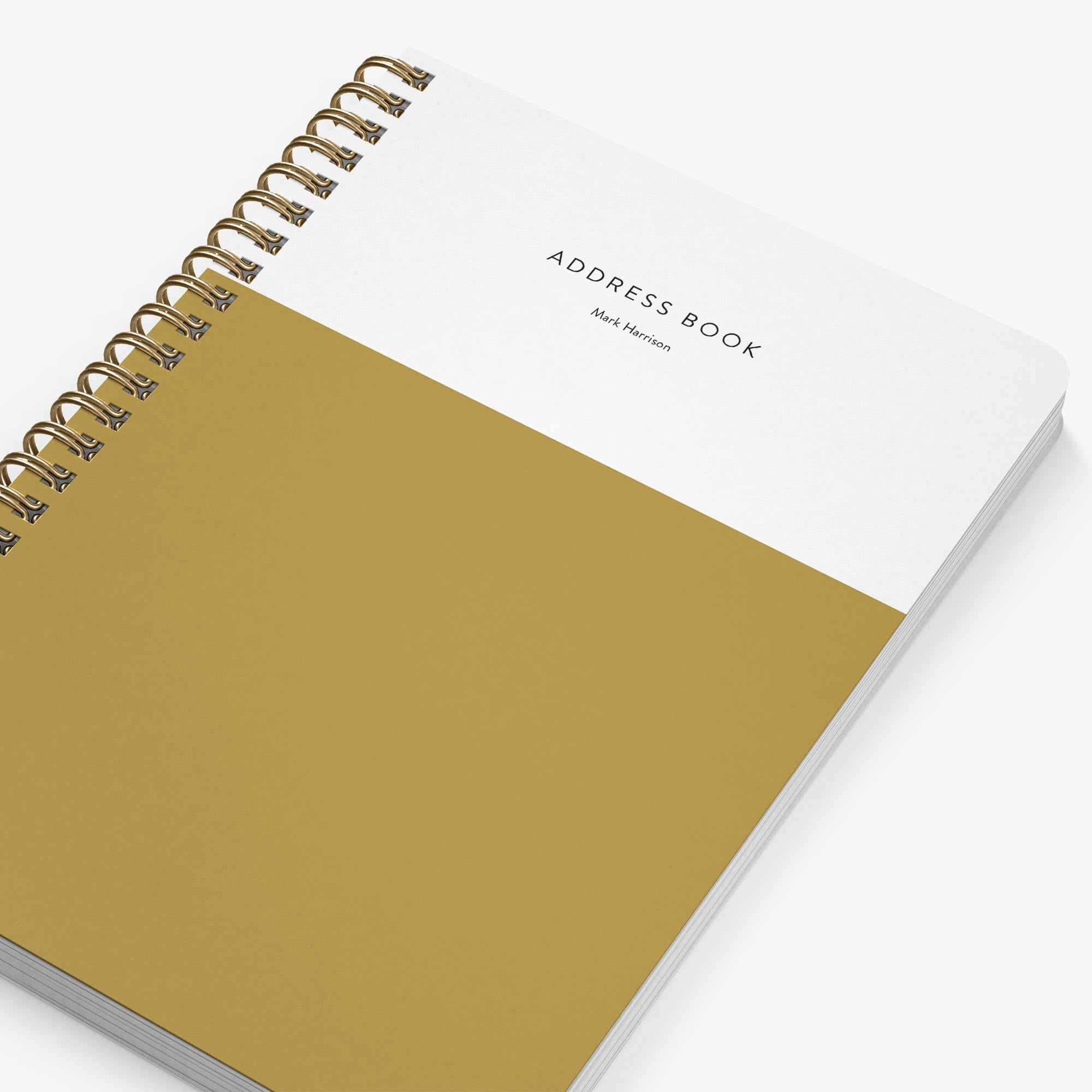 Address book with gold spiral binding and mustard yellow cover on a white background