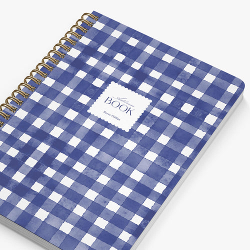 Blue and white checkered notebook with gold spiral binding on a white background