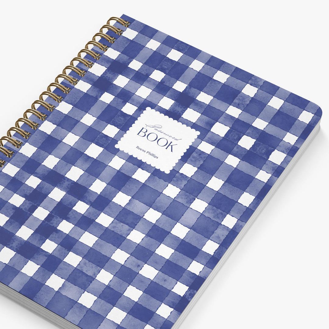Blue and white checkered notebook with a gold spiral binding on a white background