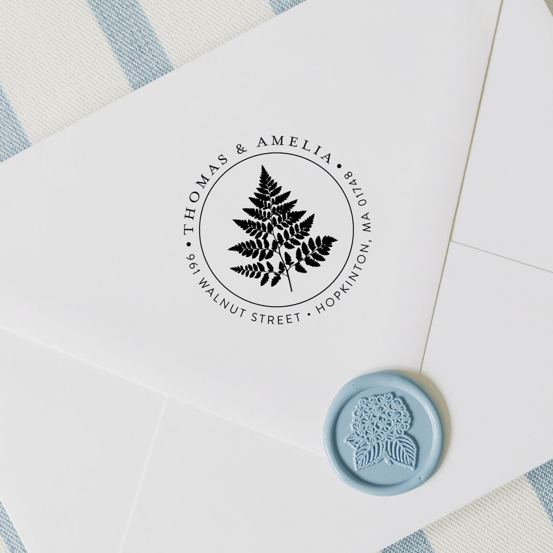 Personalized address stamp with botanical fern design on a white envelope with blue wax seal