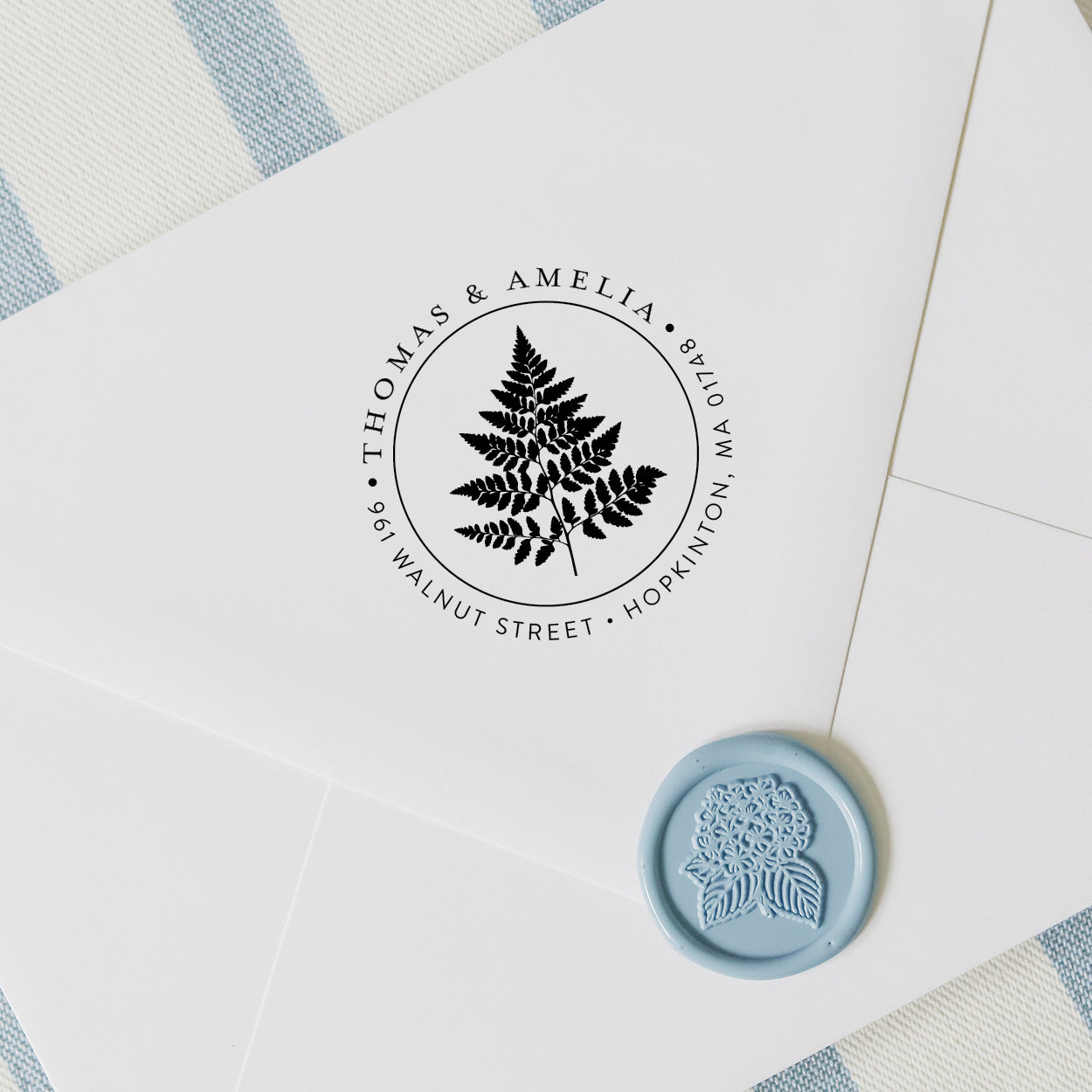 Personalized address stamp with botanical fern design on a white envelope with blue wax seal