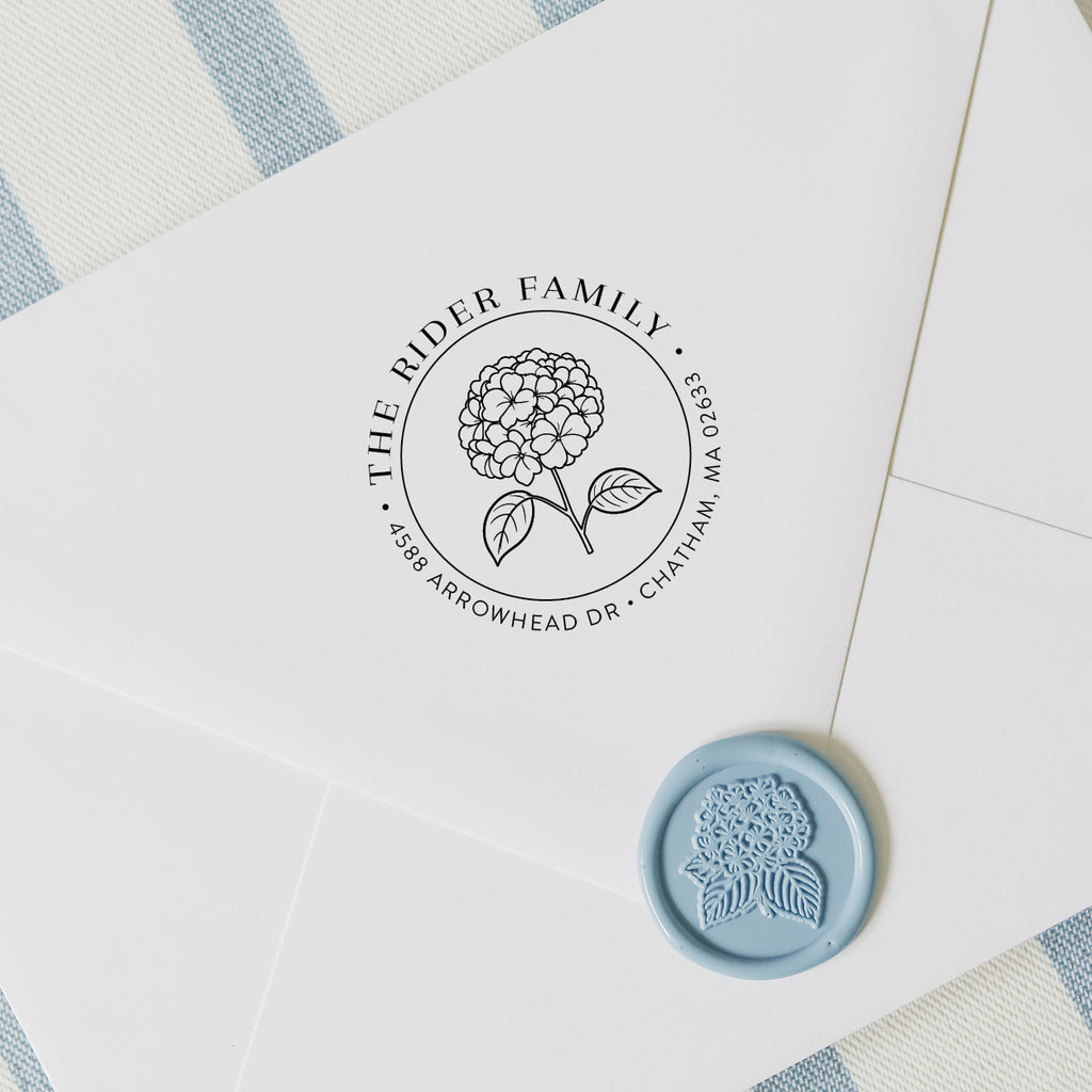 Custom hydrangea address stamp on a white envelope with wax seal and blue and white striped background