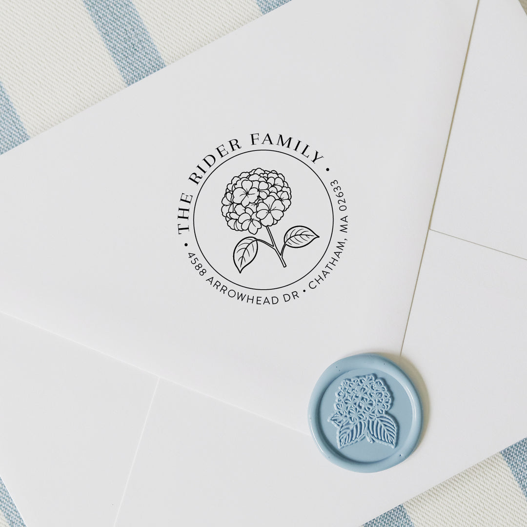 Custom hydrangea address stamp on a white envelope with wax seal and blue and white striped background
