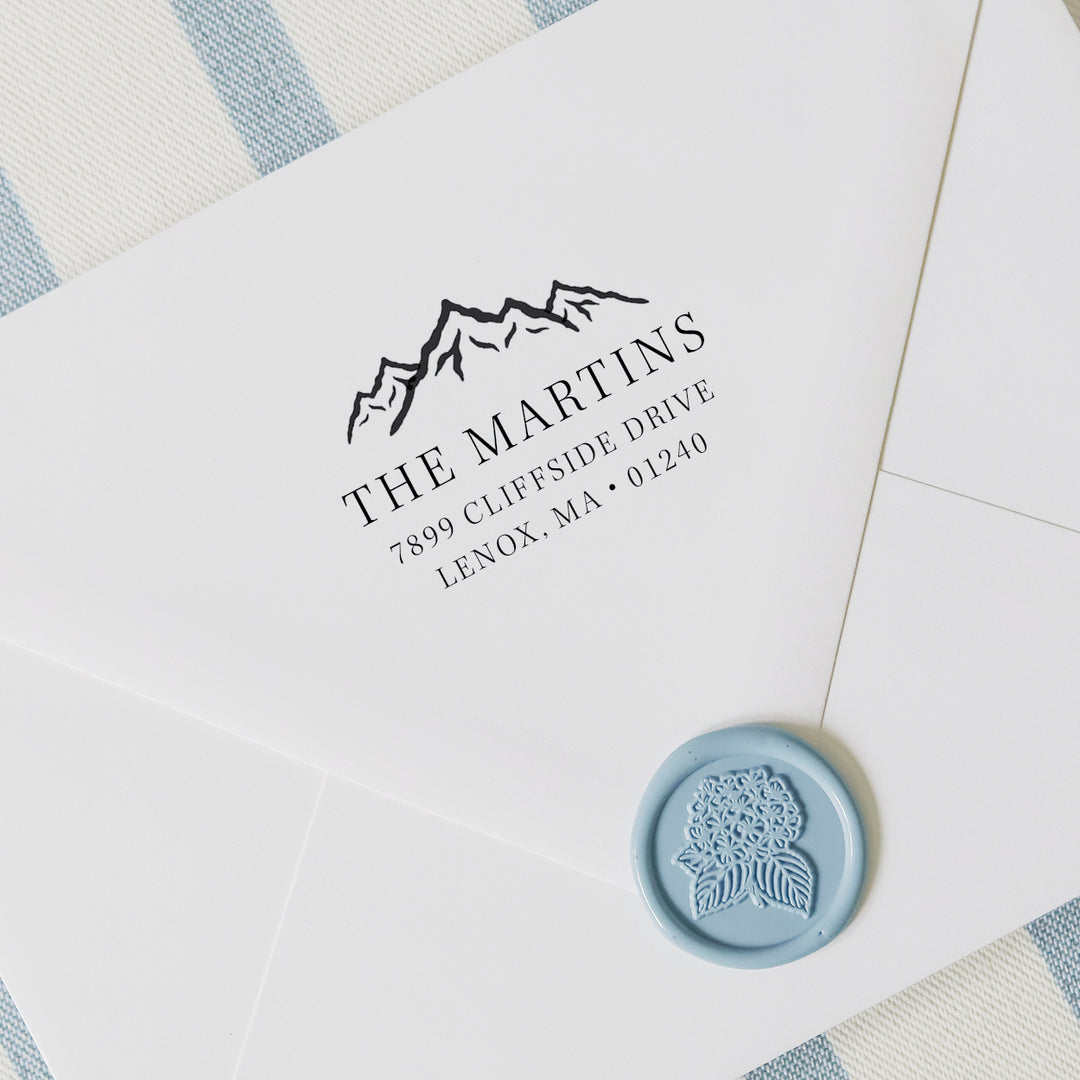 Personalized address stamp with mountain range on a white envelope with wax seal and striped background