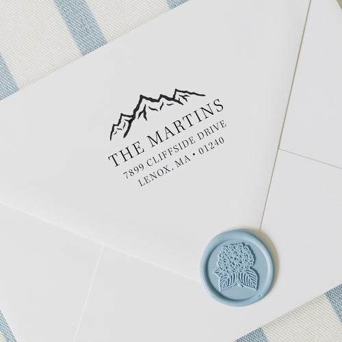 Personalized address stamp with mountain range on a white envelope with wax seal and striped background