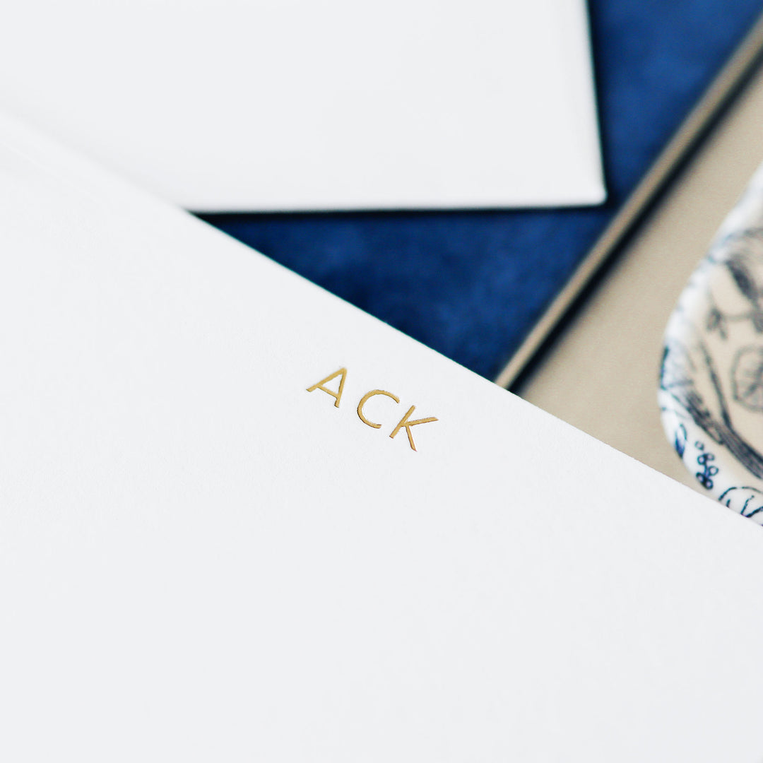 A detail shot of the petite gold foil monogram on a white cotton paper card