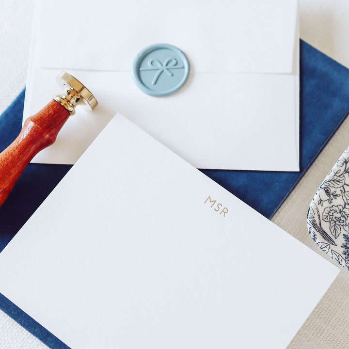 A monogram note card on white cotton paper with envelope and wax seal