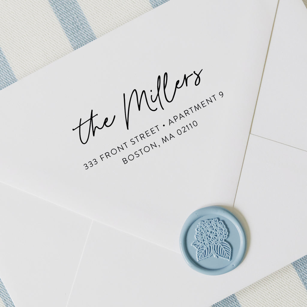Personalized address stamp with modern script design on a white envelope with blue wax seal