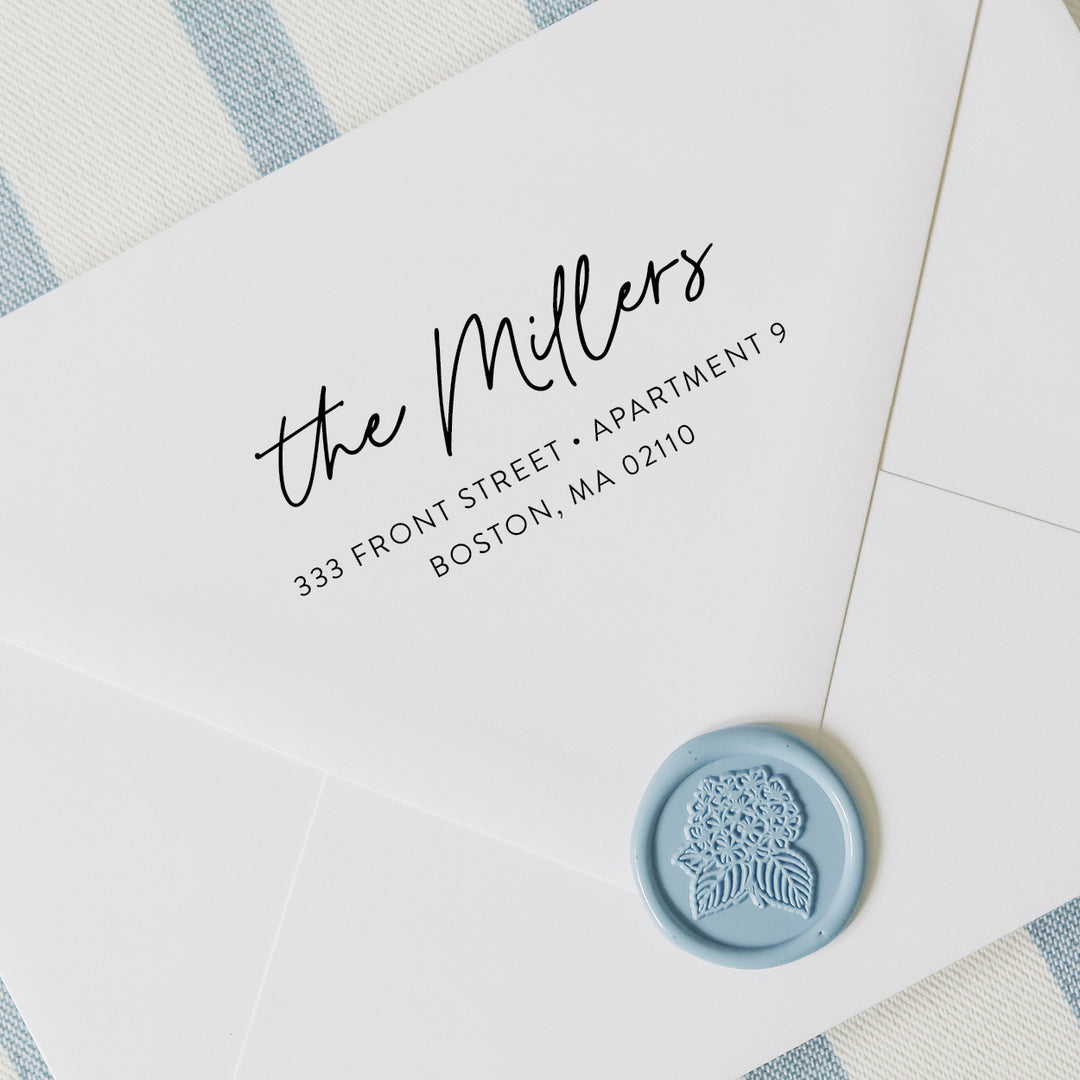 Personalized address stamp with modern script design on a white envelope with blue wax seal