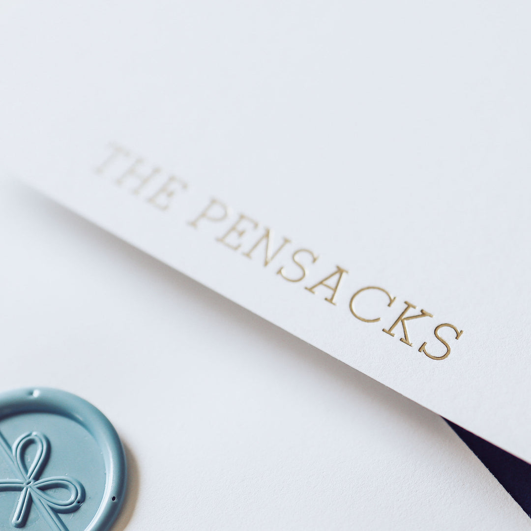 A closeup of a custom foil pressed note card on cotton paper styled with wax seal
