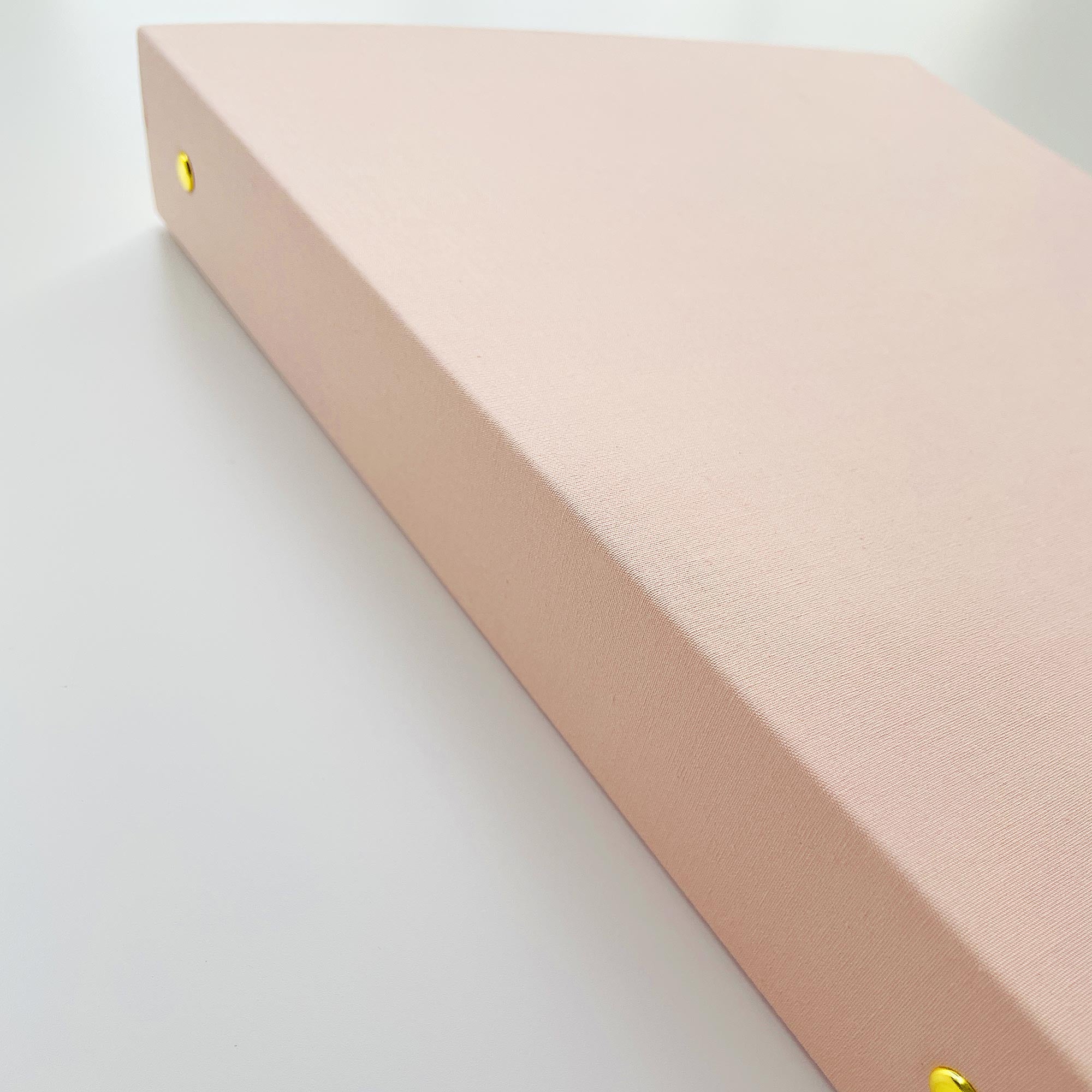 Pink linen binder with gold hardware on a white background