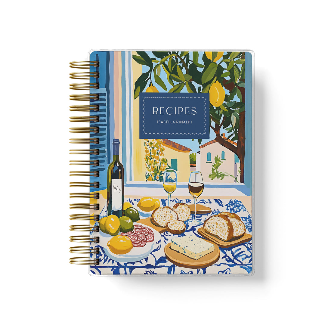 Custom recipe journal features an "al fresco" dining scene with a painting of wine, lemons, bread and villas out the window