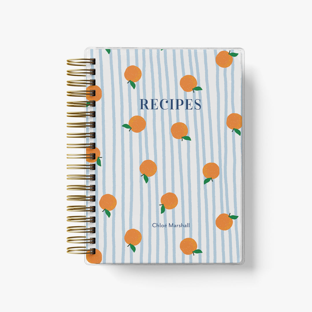 This custom recipe journal features an adorable pattern of orange fruit on a blue and white striped background