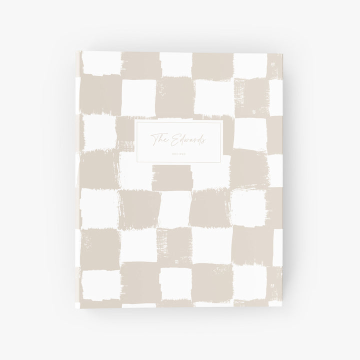Custom recipe binder with a beige and white painted checkerboard pattern personalized with a family name