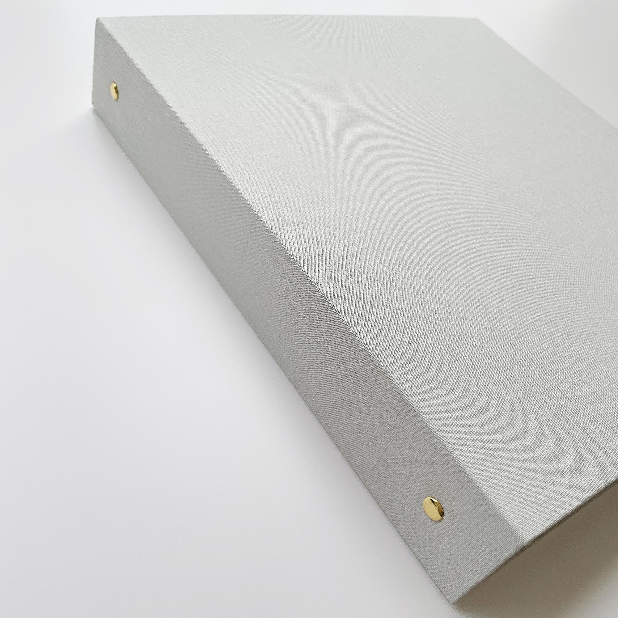 Close up of beige linen binder with gold hardware on white background